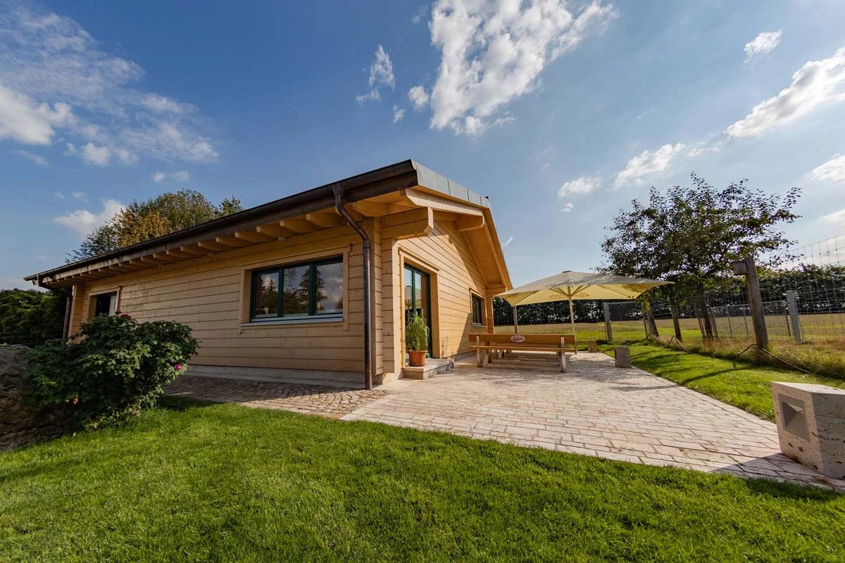 Das Blockhaus am Hotel Schwartze in Gelmeroda: Holzhaus mit Rasen, Weg und Terrasse unter blauem Himmel