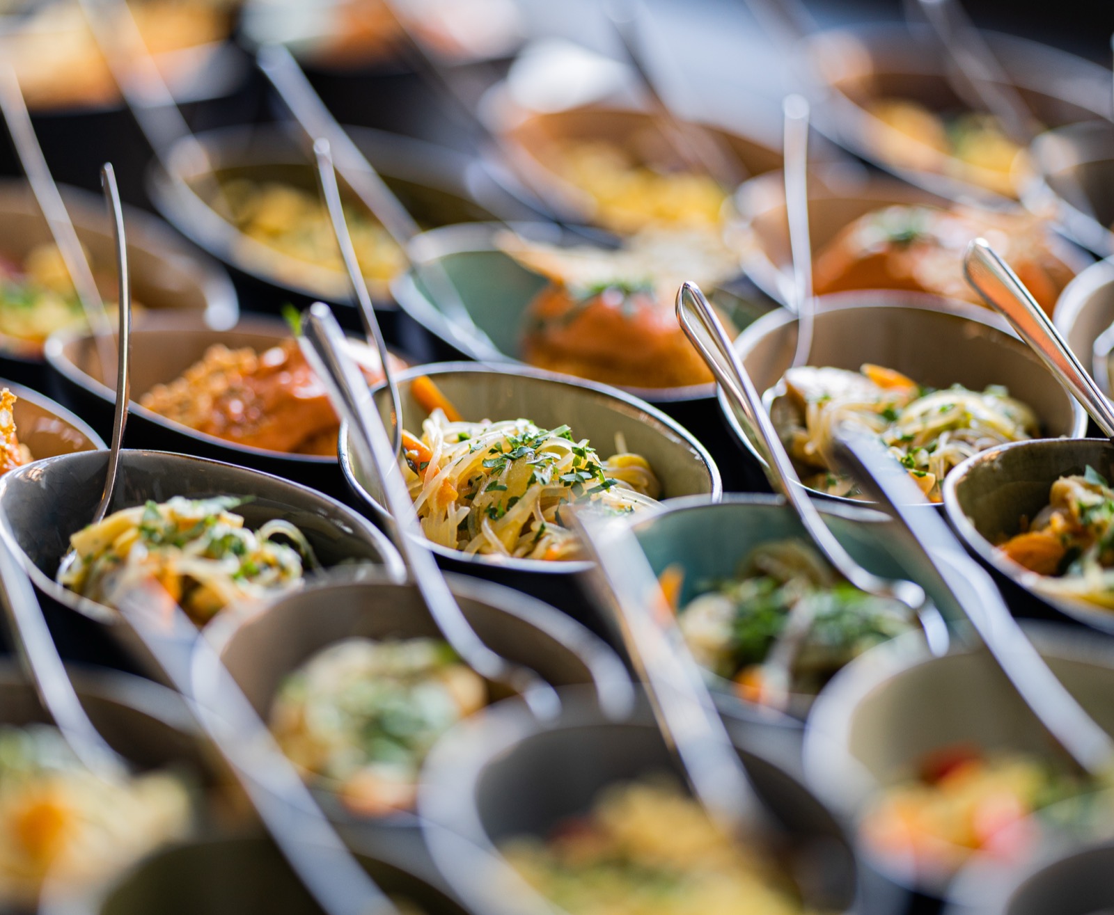 Buffet aus vielen kleinen Bowls mit Löffeln, bunt gefüllt in Reihen