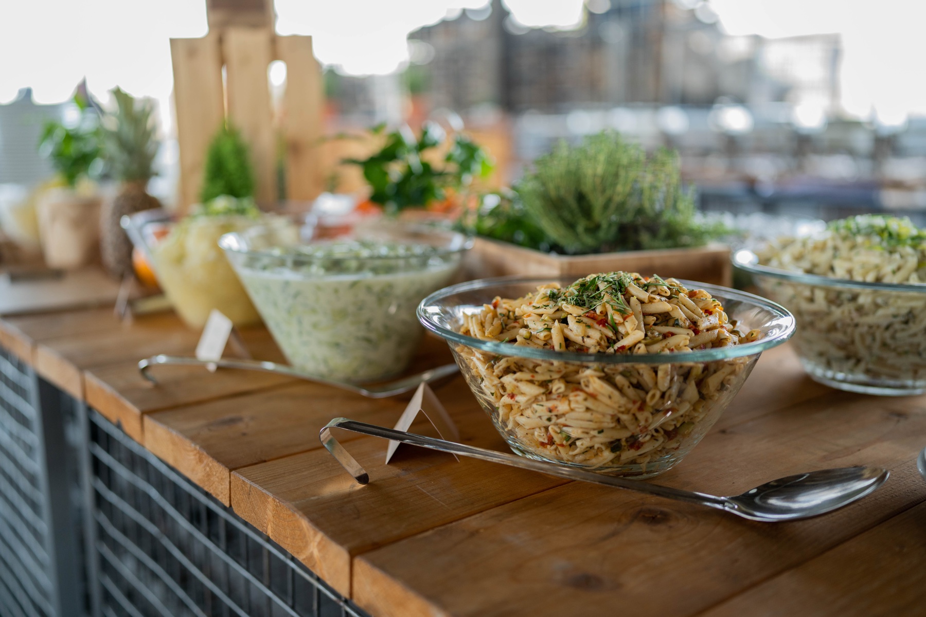 Buffet mit Salatschüsseln, Schalen und Vorlegebesteck auf Holztresen