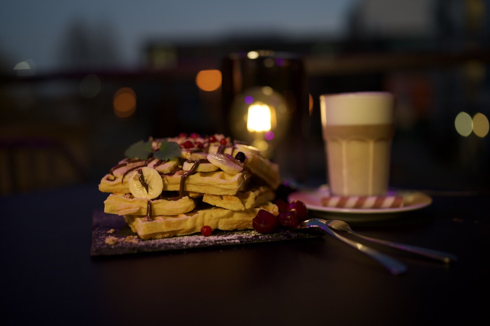 Waffeln mit Latte macchiato und Windlicht im Abendlicht