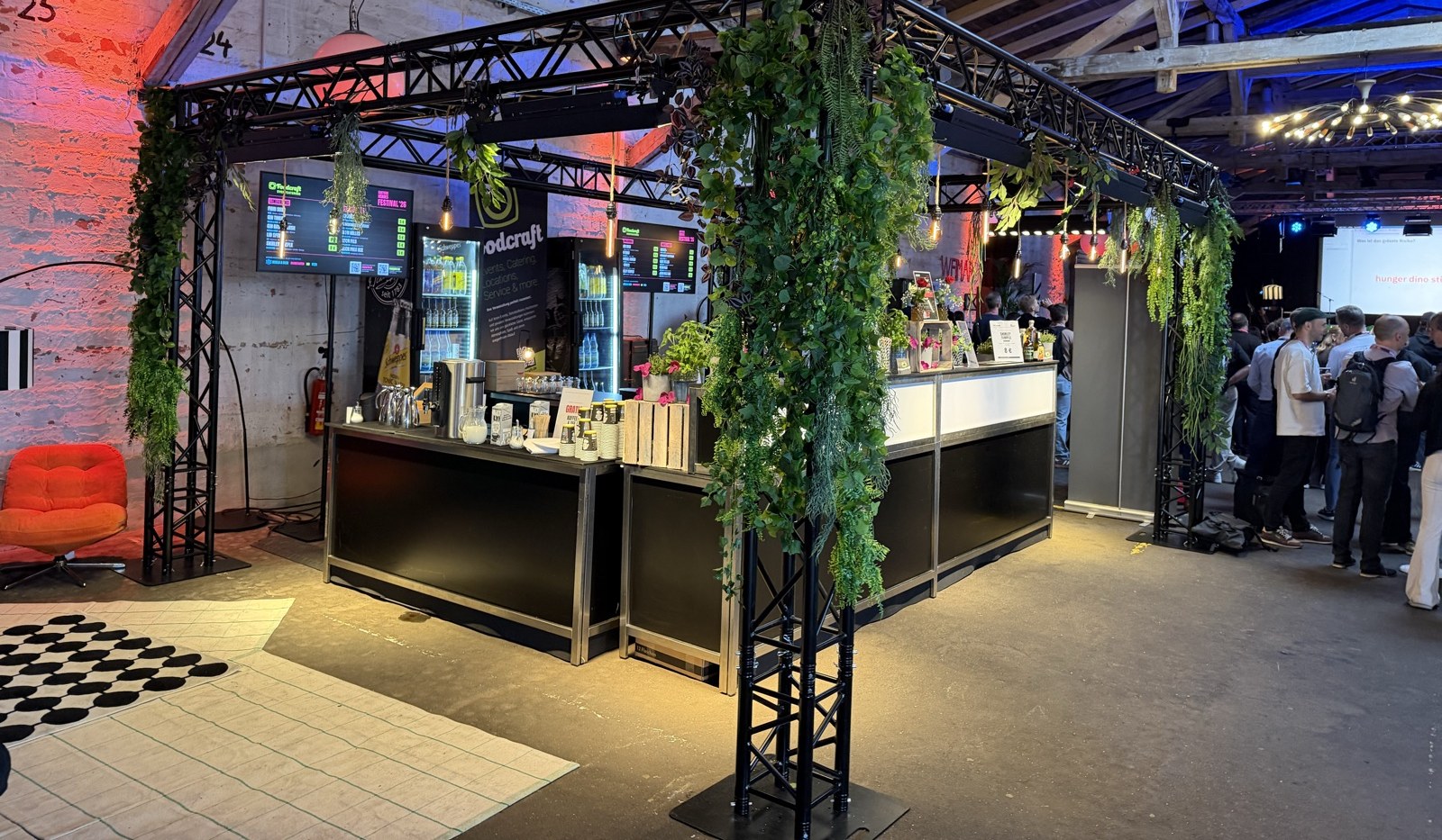 Frontale Thekenansicht der Modulbar mit Screens und Gästen im Hintergrund