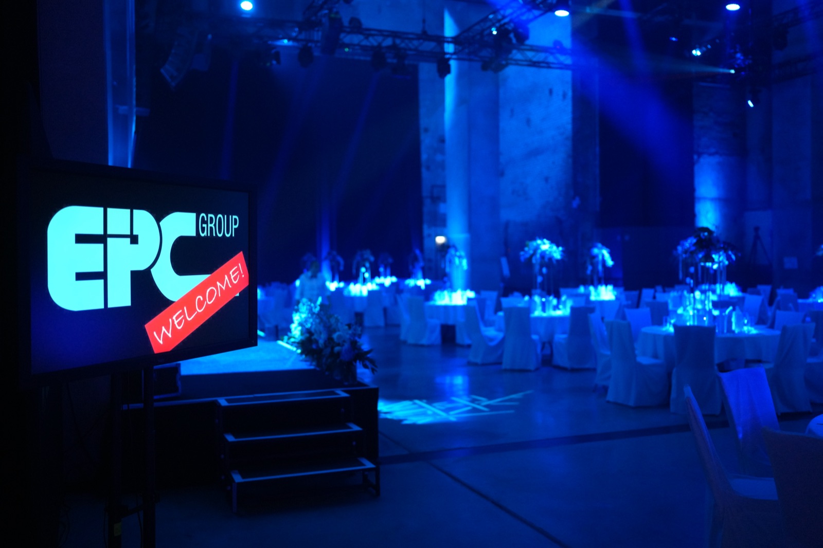 Eingedeckte Tafeln im blauen Saal mit EPC-Group-Anzeige an der Bühne