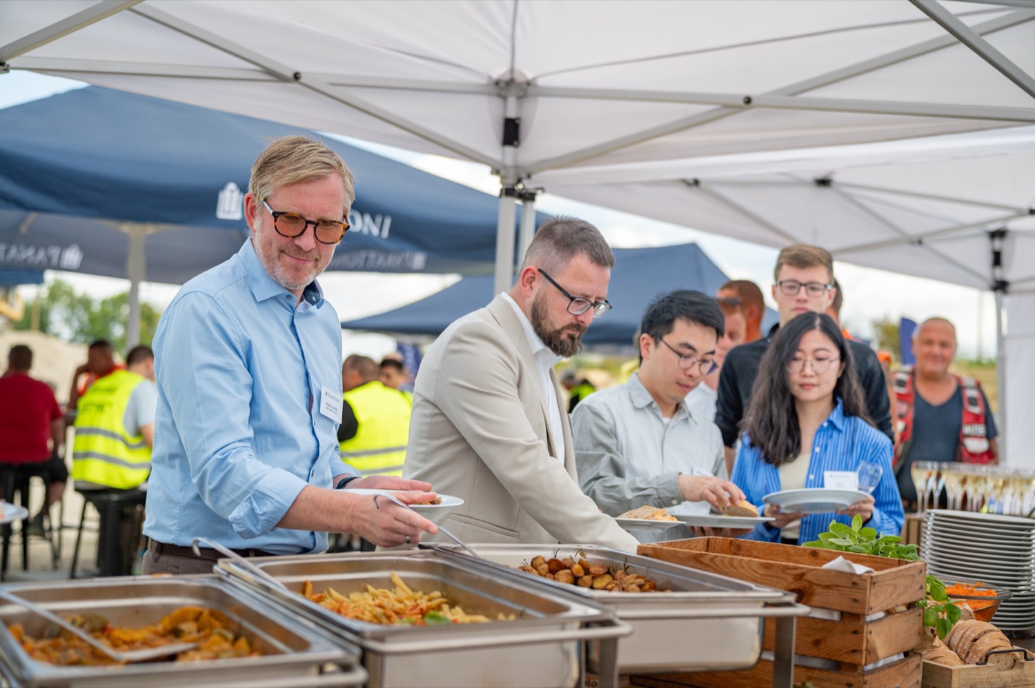 Gäste bedienen sich am Buffet unter dem Zeltdach beim Richtfest in Nohra