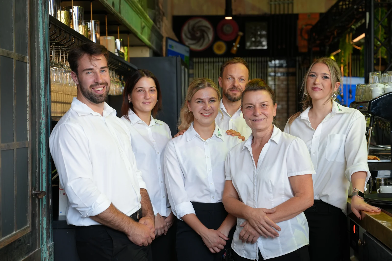 Sechs Mitglieder des Foodcraft-Serviceteams in weißen Hemden gemeinsam an der Bar