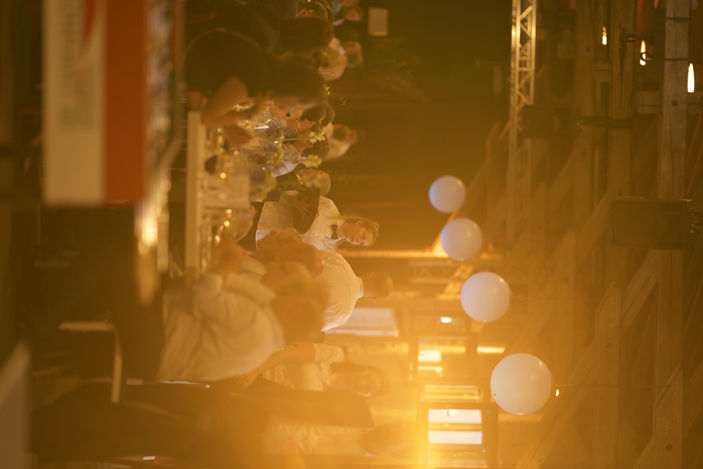Gäste an Tafeln in der Halle 6 im Zughafen am Abend